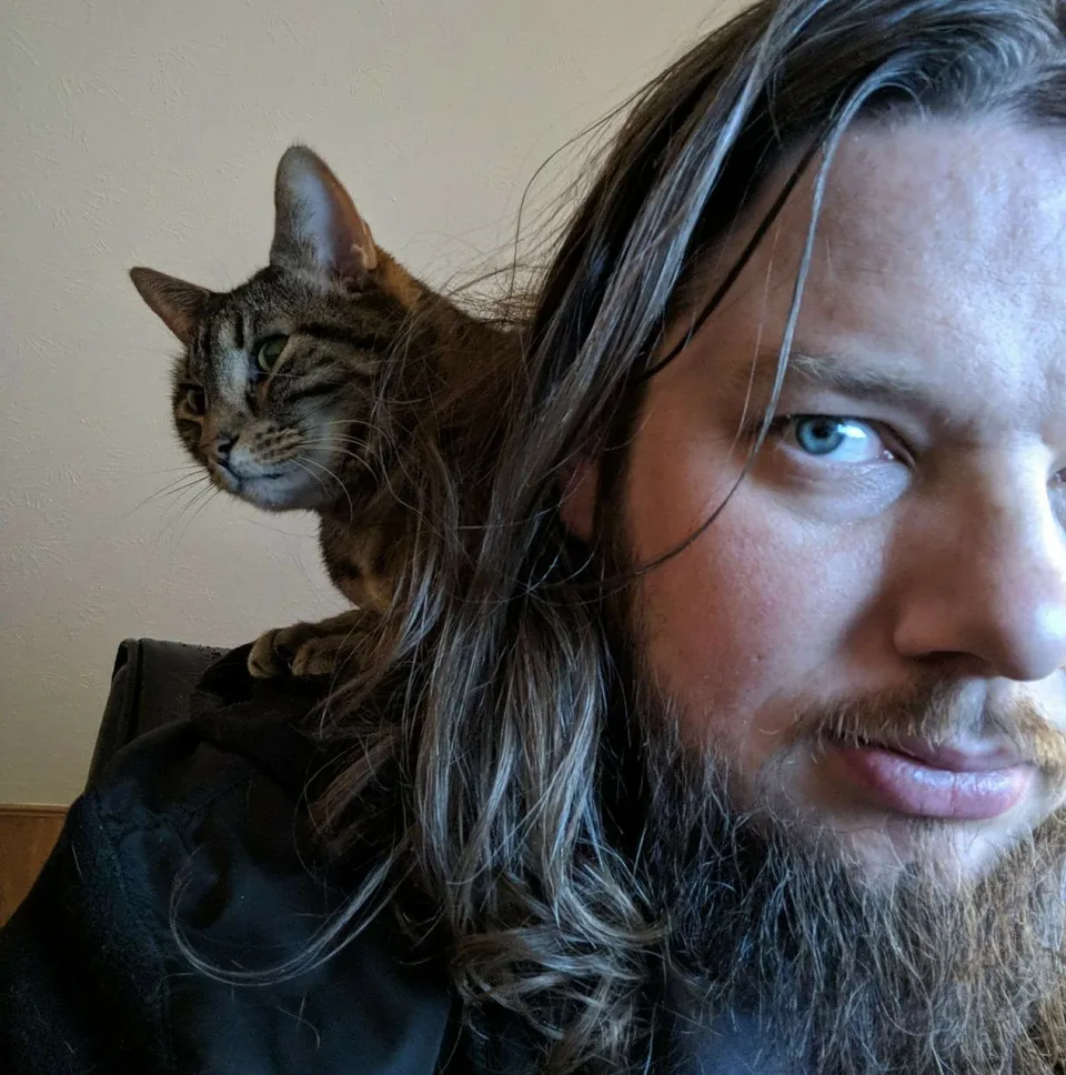 Travis with his cat perched on his shoulder